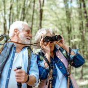 senior couple hiking in a forest woman with binoculars